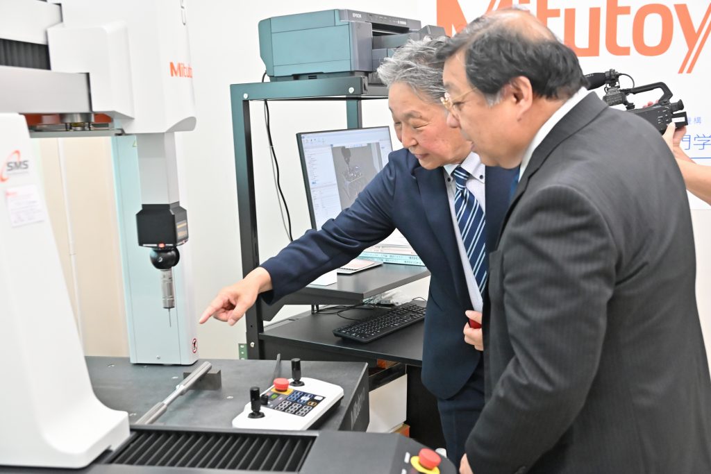 鶴見校長に機器の説明をする加納取締役常務執行役員